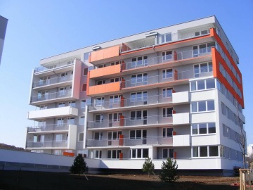 Moderní bytový dům Milíčovský háj s oranžovými prvky a balkony pod modrou oblohou.