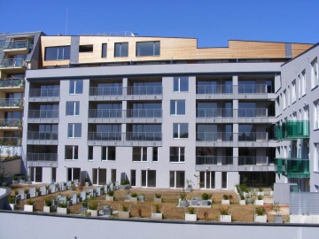 Moderní bytový dům s balkony s kovovým a skleněným zábradlím.