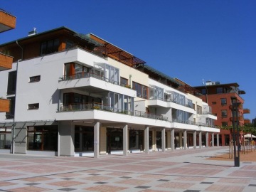 Moderní bytový komplex Dolní Břežany s balkony na pěší zóně za slunečného dne.