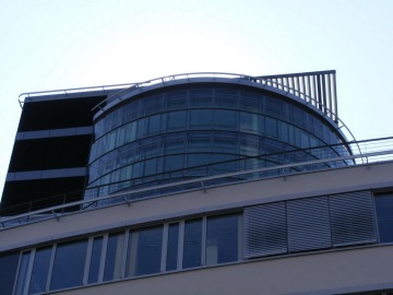 Moderní budova Trianon s prosklenou kopulí a horizontálními lamelami na střeše.