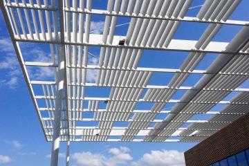 Bílé lamelové stínící zařízení proti modré obloze s bílými mraky Laserové centrum ELI.