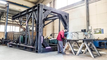 Pracovník svařuje kovovou konstrukci pod sila.