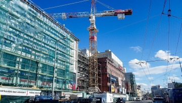 Stavba nebo rekonstrukce budovy s jeřábem uprostřed města za slunečného dne.