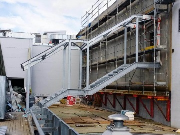 Ocelové schodiště na stavení ploše s lešením a zdivem.