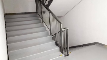 Šedé schodiště s kovovým zábradlím v budově.