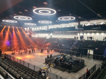 Velká koncertní hala O2 Universum Praha s kruhovými světly na stropě, diváky na tribunách a světelnou show na jevišti.