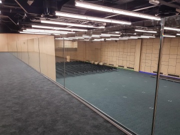 Velký konferenční sál O2 Universum Praha se skleněnou stěnou, tmavým kobercem a řadami židlí uprostřed.