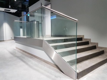 Moderní schodiště s nerezovým zábradlím a skleněnými panely v moderním interiéru O2 Universum Praha.