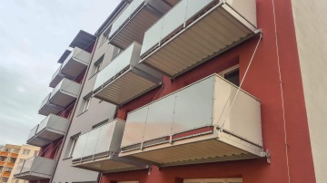 Bytový dům Bechyně s moderními balkonovými panely z kovu a skla, pohled z ulice.