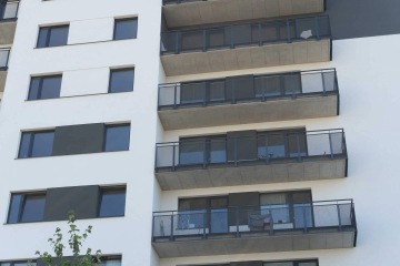 Moderní novostavba s řadou balkonů se zábradlím s tahokovovou výplní.