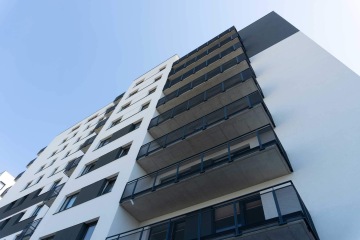 Moderní bytový dům s balkony se zábradlím s tahokovovou výplní.