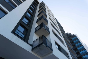 Moderní bytový dům s balkony se zábradlím s tahokovovou výplní.