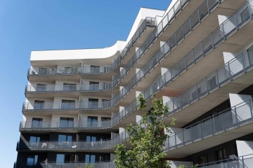 Moderní bytový dům s balkony se zábradlím s tahokovovou výplní.