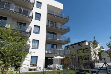 Moderní bytový dům s balkony se zábradlím s tahokovovou výplní.