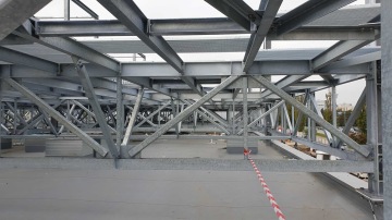 Kovová nosná konstrukce s trámy a vzpěrami na střešní plošině Škoda Auto - Centrální kuchyně.