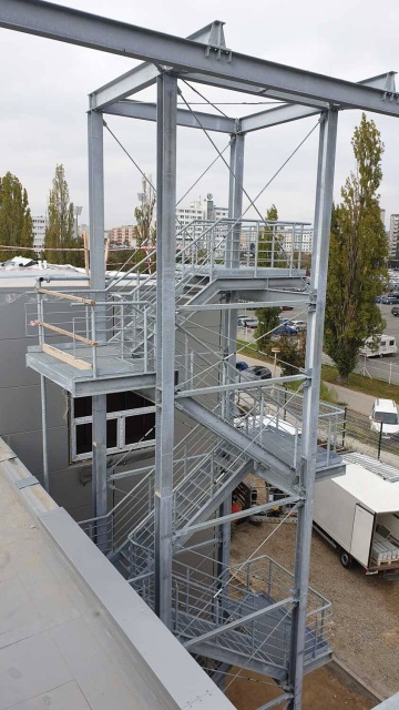 Ocelové požární schodiště u budovy Škoda Auto - Centrální kuchyně s výhledem na městskou část.