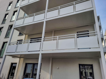 Moderní bílý balkonový systém na budově Haardtring Darmstadt s prosklenými okny a čistou architektonickou linií.