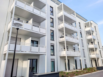 Moderní bytový dům Haardtring Darmstadt s bílými balkony a zahradou v popředí.