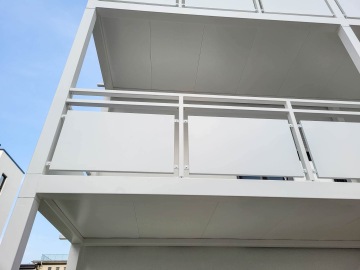 Bílý moderní balkon Haardtring Darmstadt s čistými liniemi proti modré obloze.