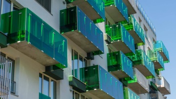 Balkony s průhledným zeleným plastovým zábradlím na moderní bytové budově Tesla Vršovice.