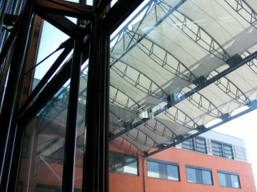 Moderní kovová konstrukce společnosti Skanska a skleněná střecha nad oranžovou budovou.