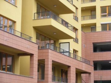 Moderní bytový komplex Vokovice se žlutými a hnědými fasádami a prostornými balkony.