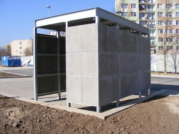 Betonový přístřešek na odpadky u sídliště Milíčovský háj za slunečného dne.