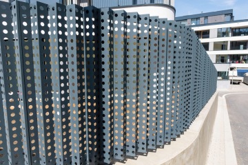 Šedý perforovaný plechový plot v moderním městském prostředí Rezidence MAISON Ořechovka.
