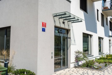 Vchod do moderní budovy s prosklenou stříškou.