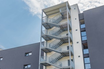 Nouzové venkovní schodiště moderní budovy AFI Home Kolbenova pod jasnou oblohou.