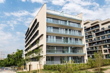 Moderní bytový dům AFI Home Třebešín s balkony pod modrou oblohou.