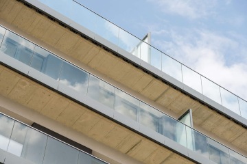 Moderní prosklené balkony výškového domu AFI Home Třebešín na modré obloze.