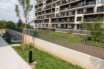 Moderní bytový dům AFI Home Třebešín s balkony a zelenou plochou před ním.