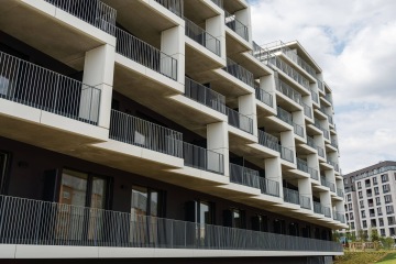 Moderní bytová budova v Rezidenční čtvrti Hagibor s balkóny a kovovým zábradlím, obloha s mraky v pozadí.