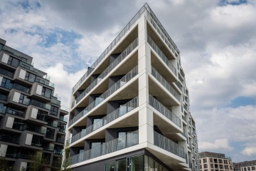 Moderní bytový dům v Rezidenční čtvrti Hagibor s balkony a skleněnými zábradlími pod oblačnou oblohou.