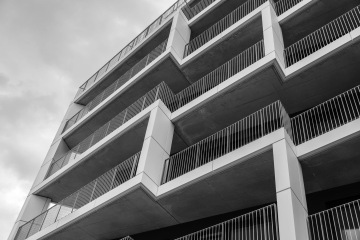 Moderní fasáda budovy v Rezidenční čtvrti Hagibor s pravidelnými balkony a zábradlím proti šedé obloze.