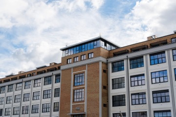 Moderní bytový dům YIT Parvi Cibulka s velkými okny pod modrou oblohou.