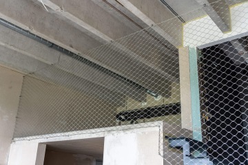 Ochranná síť natažená vodorovně pod stropem budovy Vanguard Praha, kryjící otvor u schodiště.