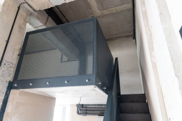 Kovové schodiště s perforovanými panely v betonové budově Vanguard Praha.