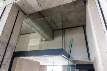 Skleněné zábradlí na betonovém schodišti Vanguard Praha s viditelnými vestavěnými kabely.