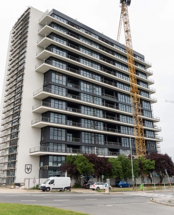 Vícepatrová budova Vanguard Praha s jeřábem uprostřed stavby, auta zaparkovaná poblíž.