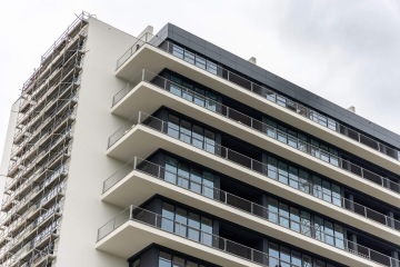 Moderní bytová budova Vanguard Praha s balkony a lešením na boku.