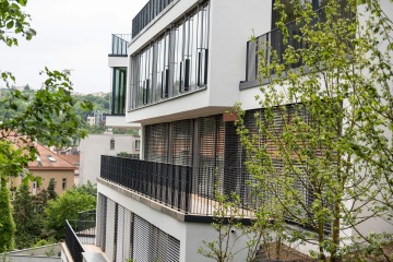 Moderní bytový dům Rezidence Erbenova s velkými prosklenými okny a balkony, obklopený zelení.