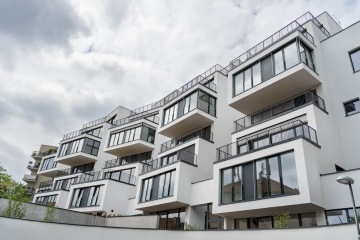 Moderní bytová architektura Rezidence Erbenova s velkými prosklenými balkony pod zamračenou oblohou.