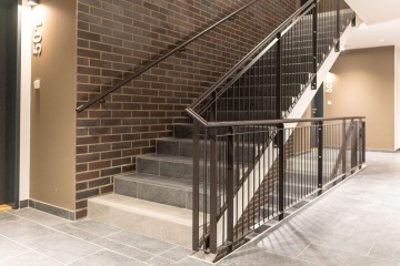 Schodiště v Britské Čtvrti s černým zábradlím a cihlovou zdí v interiéru budovy.