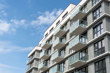 Moderní bytová budova v Britské Čtvrti s balkony pod modrou oblohou.