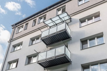 Balkony s průhledným zábradlím na moderní bytové budově BD Palackého Třinec pod modrou oblohou.