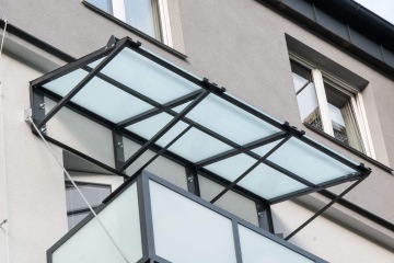 Přístřešek z matného skla na kovové konstrukci u moderní budovy BD Palackého Třinec s okny.