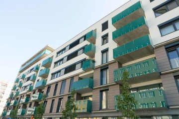 Moderní bytový dům BD Smart s balkony se skleněným zábradlím a zelenými detaily.