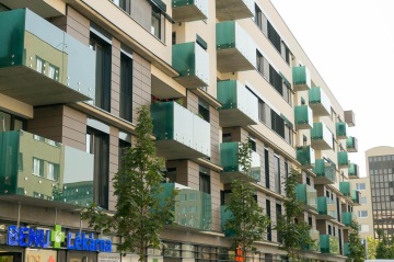 Moderní bytový dům BD Smart se zelenými skleněnými balkóny a lékárnou v přízemí.